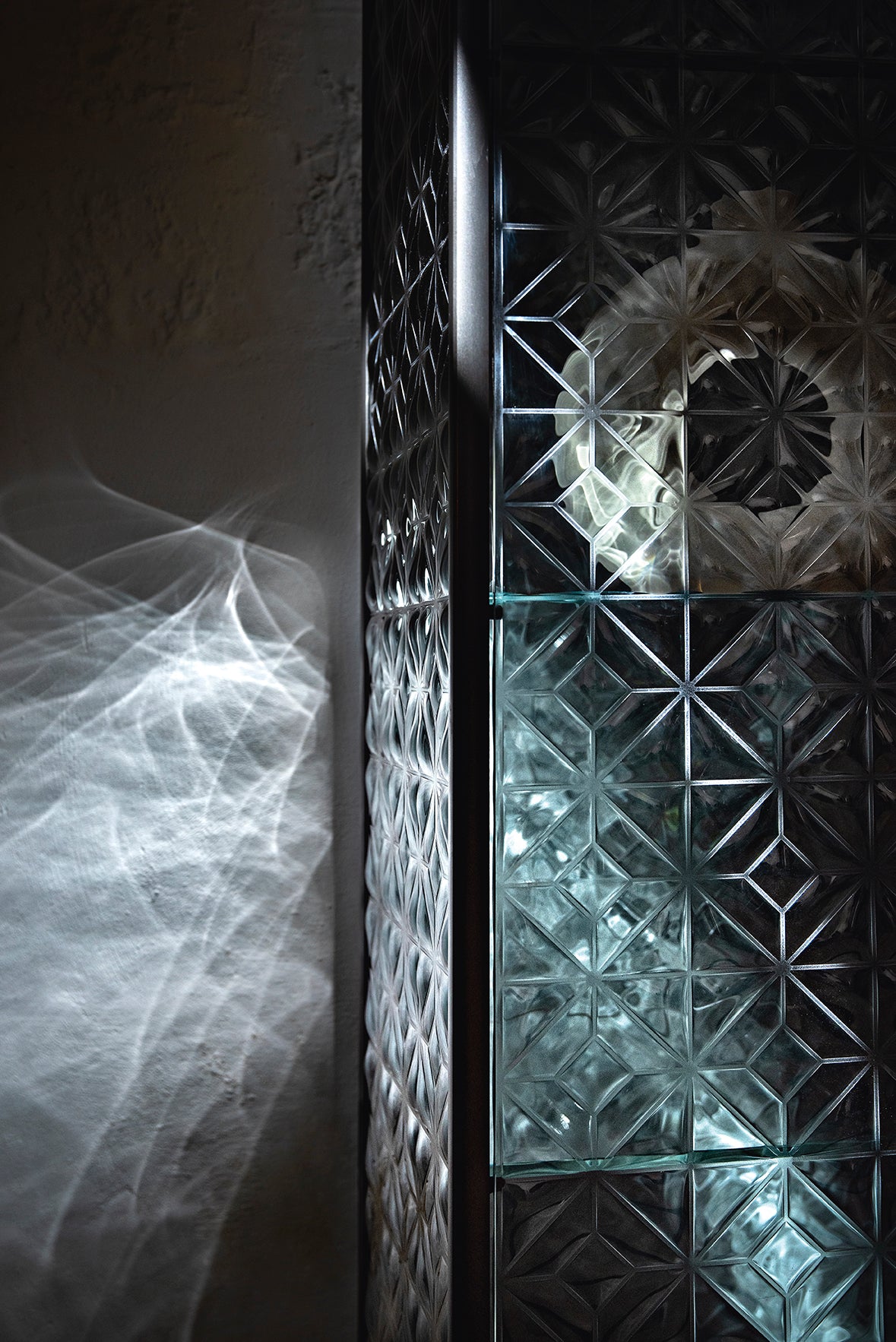 Echo display cabinet's light effect with fused glass doors with 3D geometric textures.