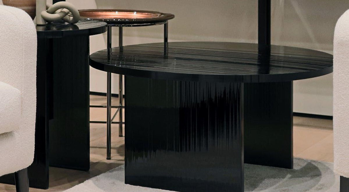Black textured glass round coffee table in a room with chairs and another table.