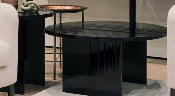 Black textured glass round coffee table in a room with chairs and another table.